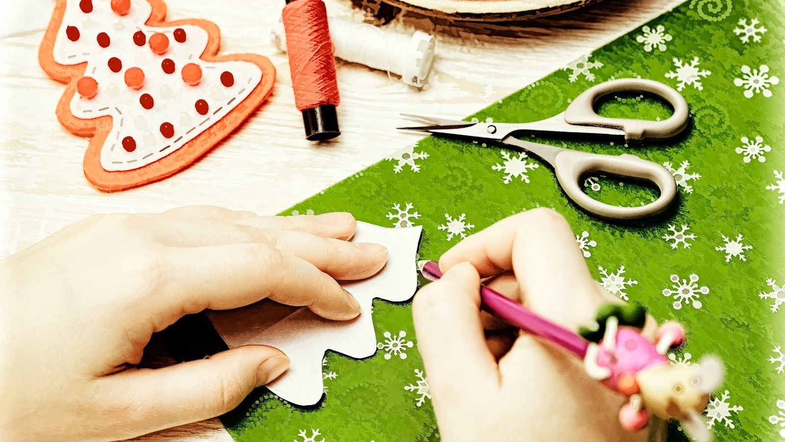 Christmas decorations being made by hand with craft items nearby, including felt, scissors and thread.